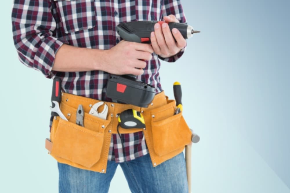 Person with tool belt holding drill, links to Handyman services page.
