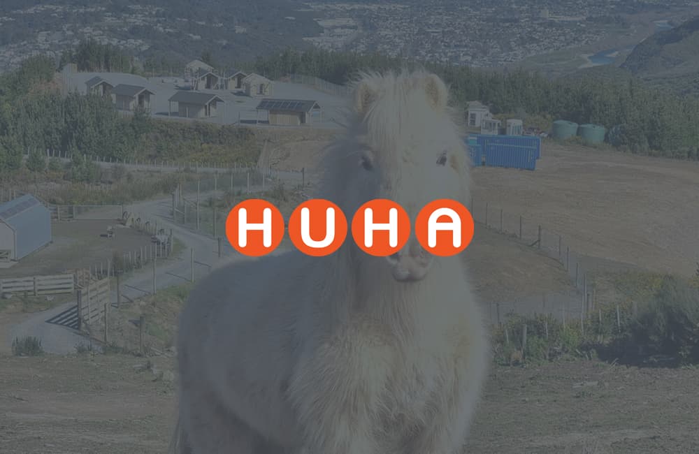 Fluffy white horse staring down the camera on a hill with a farm in the background