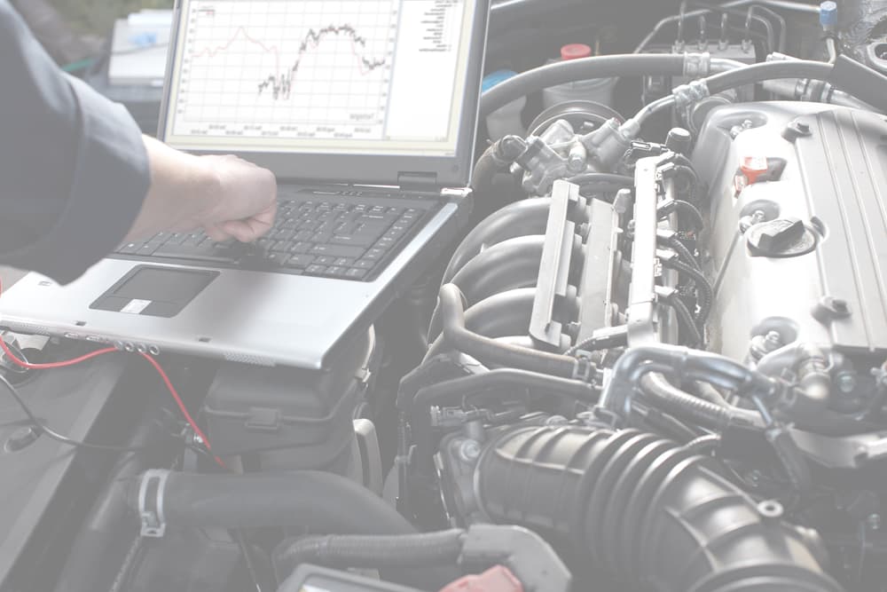 Motor Works Group specialised vehicle expert, using a laptop above the engine block