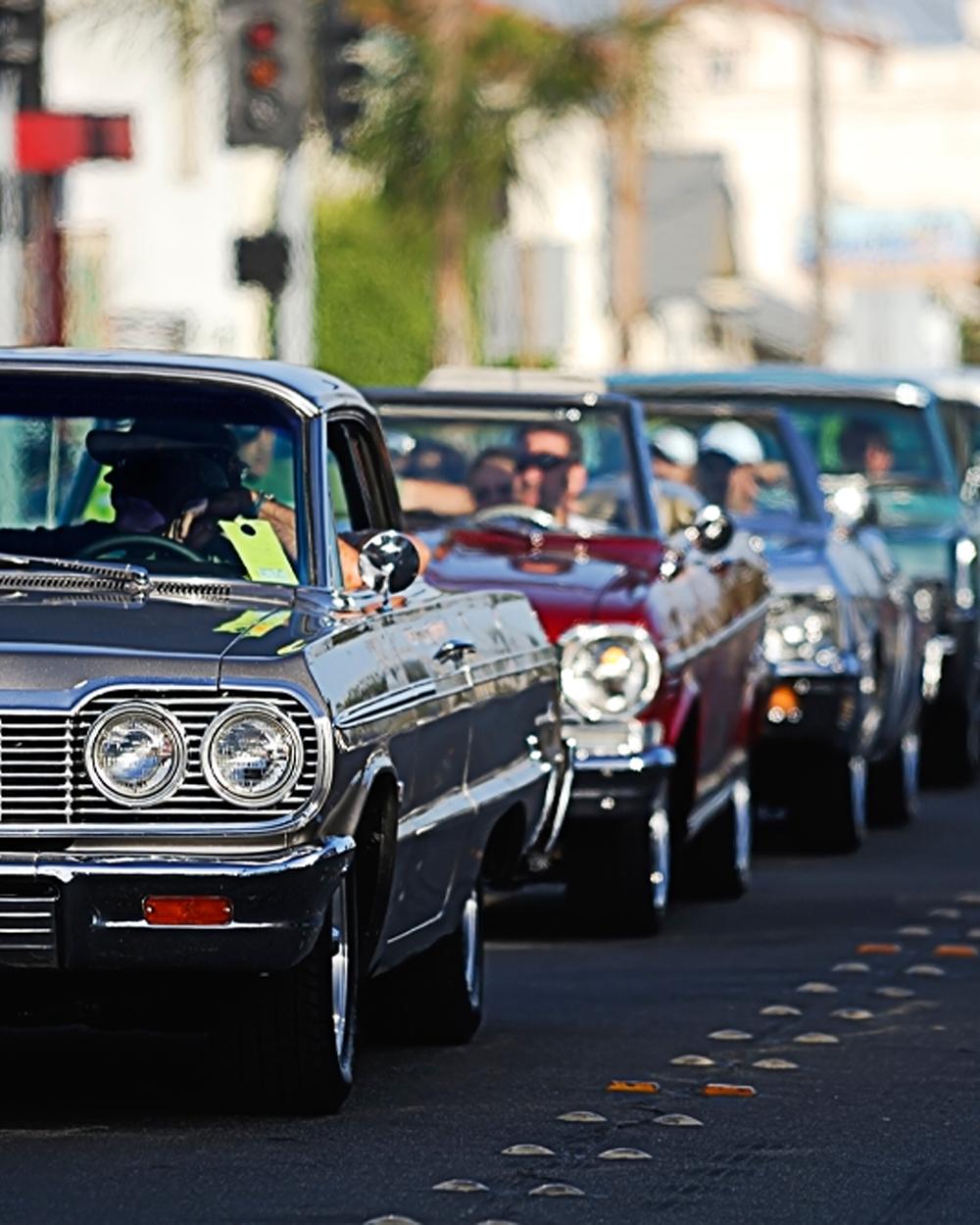 Fleet of classic vehicles lined up on the road at a car show