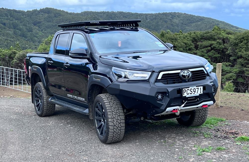 Shiny black Toyota Hilux ute parked in front a farm gate