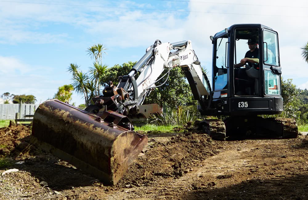 Small white digger with a bucket for excavating dirt
