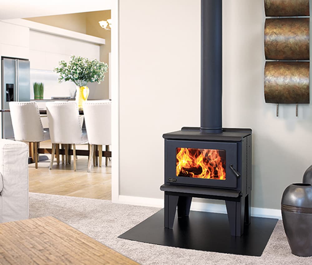 Freestanding black wood fire on a black platform protecting the beige carpet in a modern white furniture with birch wood accents