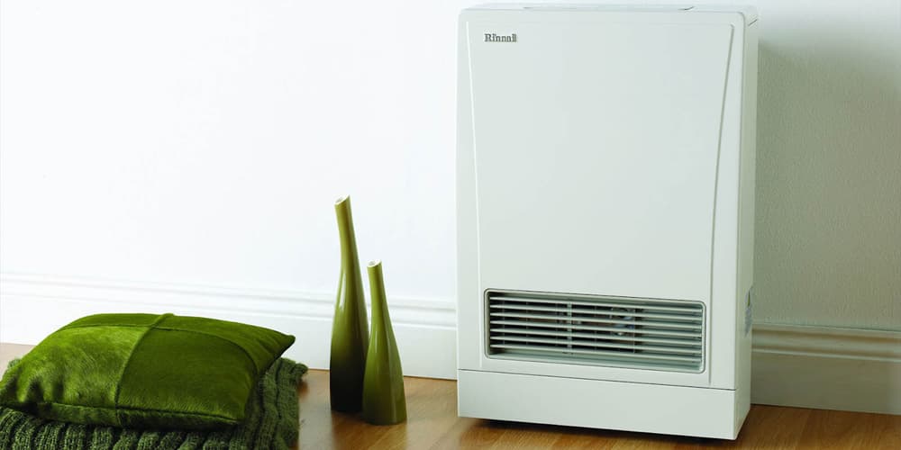 Wooden floor and a white wall with green ornaments and pillows next to a new white energysaver gas heater