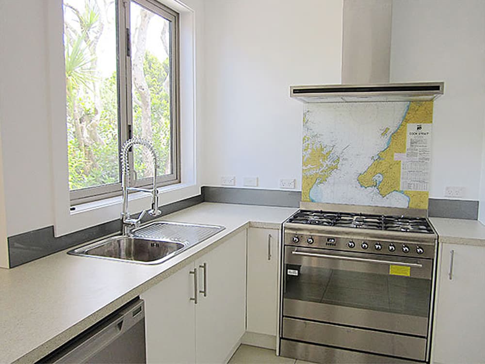 Predominantly white kitchen with a large industrial-looking oven and a splashback above it with a map of part of the world on it