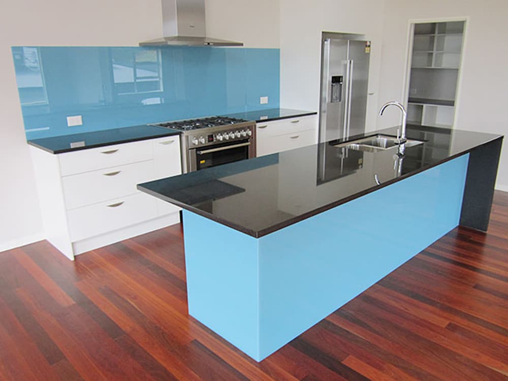 Beautiful dark wood flooring with white kitchen cabinets, black benchtops, and a baby blue splashback that matches the island