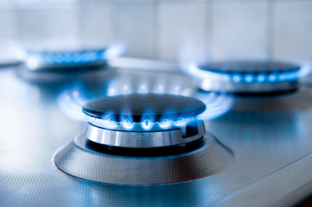Silver stovetop with three gas hobs burning blue with nothing on them