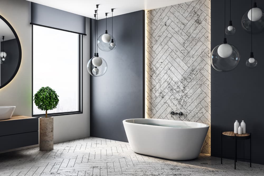 Large white freestanding bathtub filled with water, located against a white stone brick feature wall
