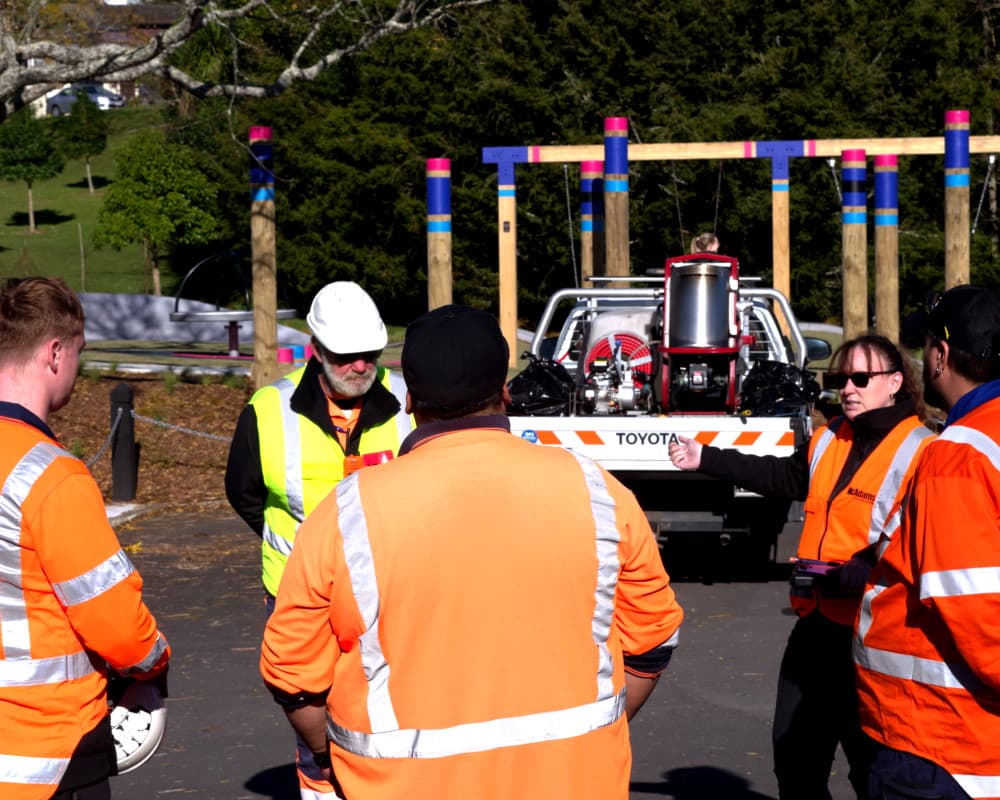 Traffic Management Waikato team members parked up at the local park, assessing a situation as they stand in a circle