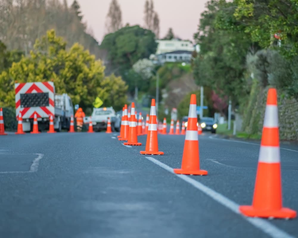 Roadworks vehicles parked up on the street with cones lining the street right down the middle letting cars past