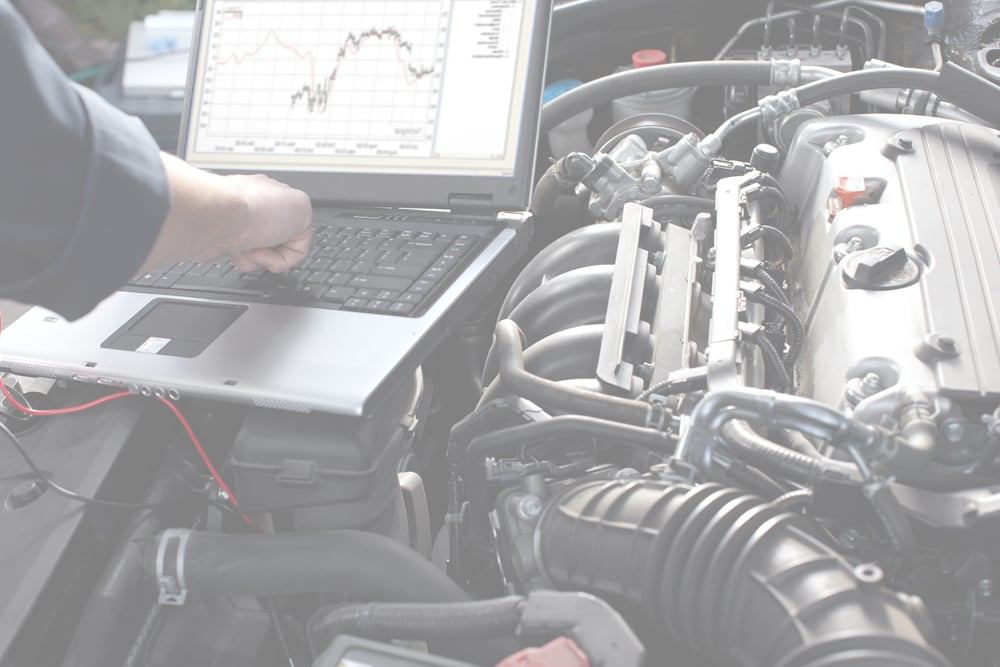 Motor Works Group specialised vehicle expert, using a laptop above the engine block