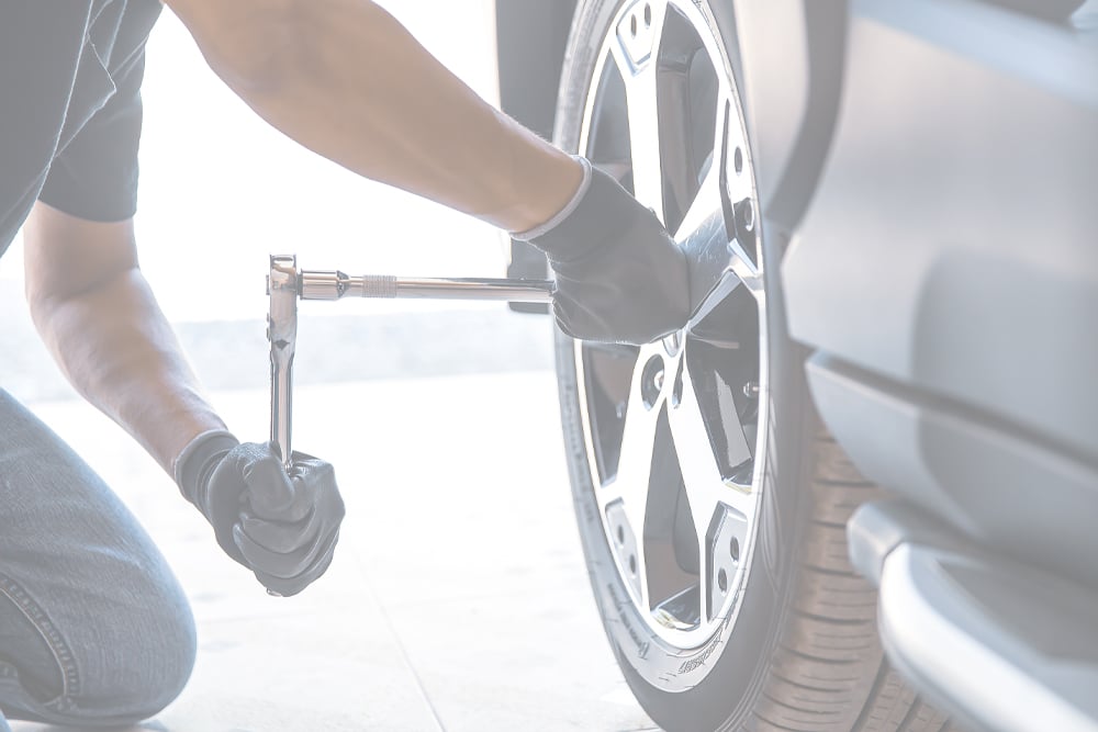 Motor Works Group team member using a socket wrench to tighten a car's wheel nuts