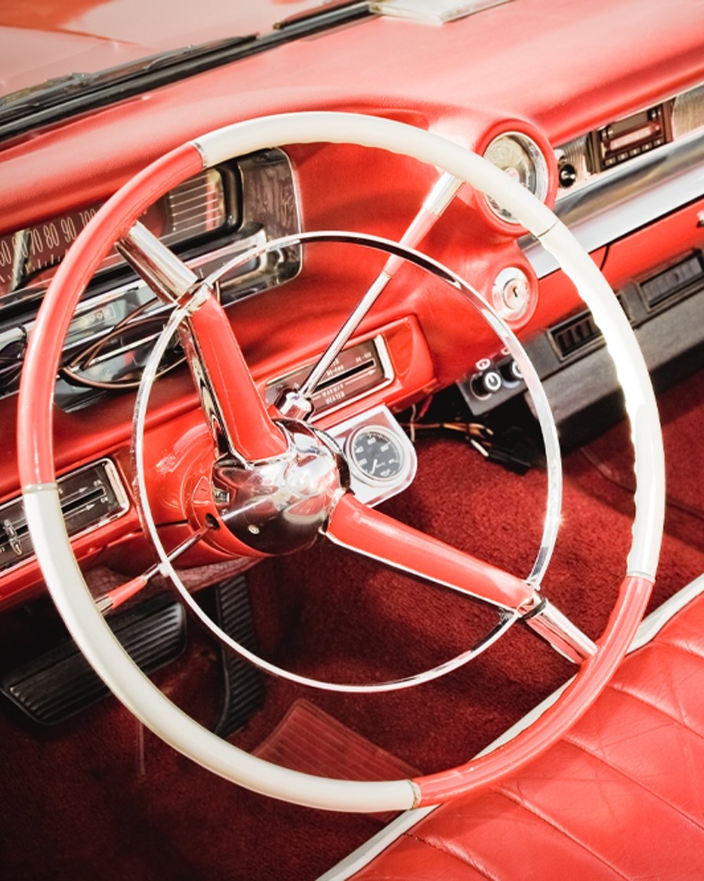 Old Classic car in pristine condition, shining red interior with a classic European style steering wheel