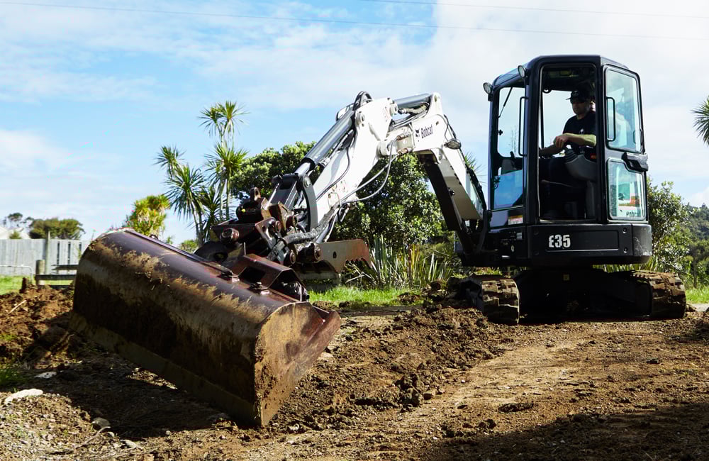 Small white digger with a bucket for excavating dirt