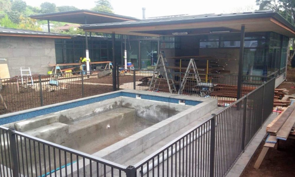 Unfinished backyard with a newly poured concrete pool and an excavated yard ready for new soil and grass