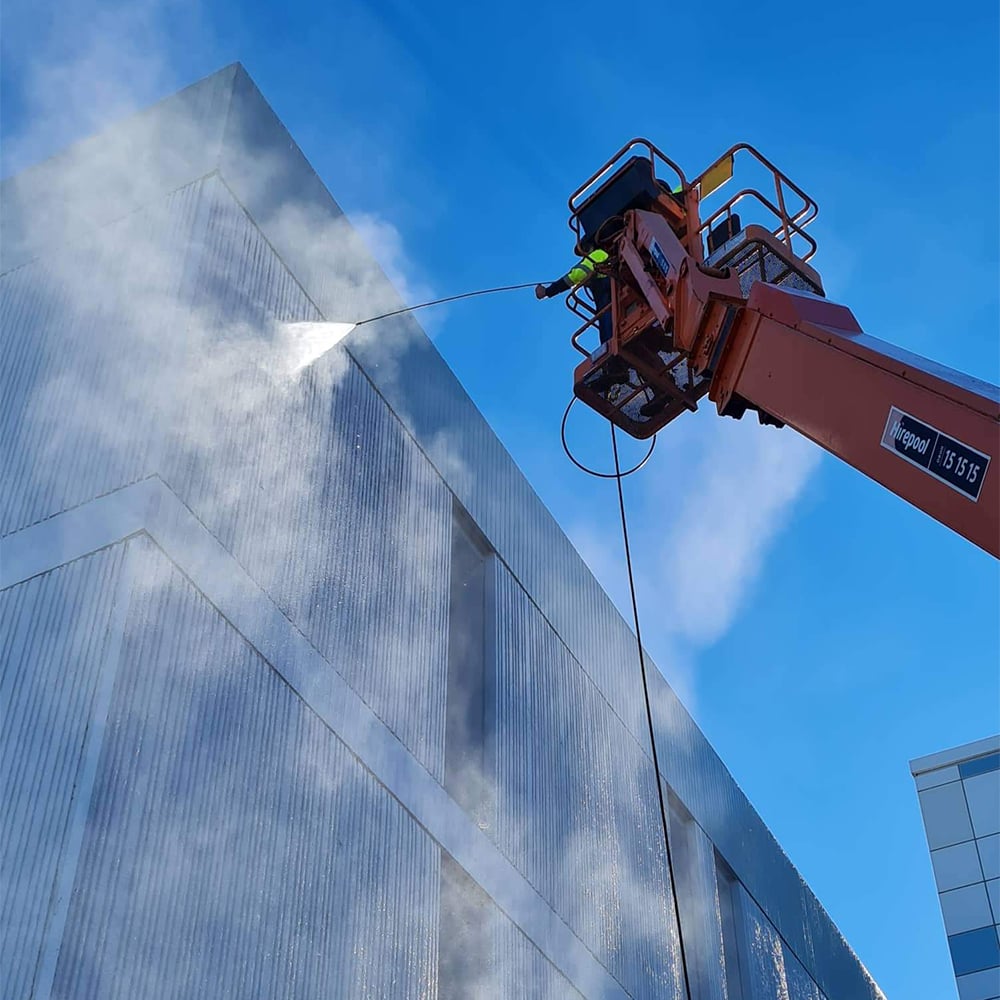 GR Abseiling using a cherry picker to power wash the exterior side of a commercial building