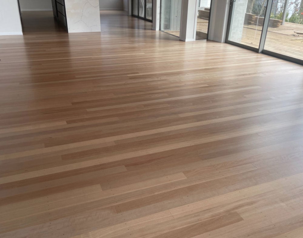 Recently polished and refinished timber floor, shining in the sun that's coming through the large glass sliding door