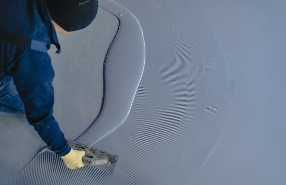 Professional painting and decorating team member spreading a grey-blue coating on a commercial floor