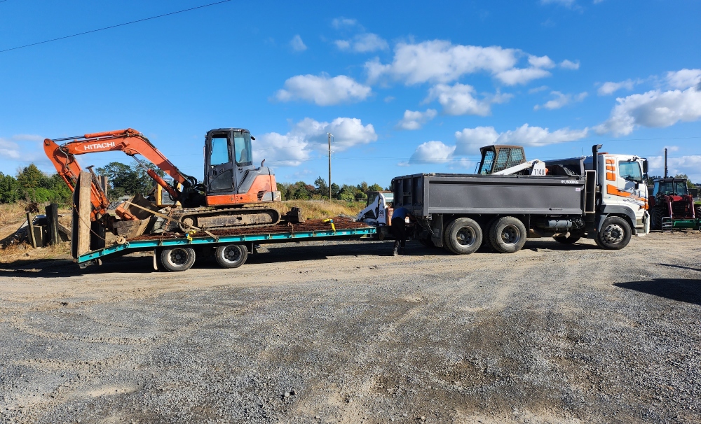 Large White and orange A1 Bobcats & Concrete truck with one carriage and a trailer with an orange digger on the back for transport