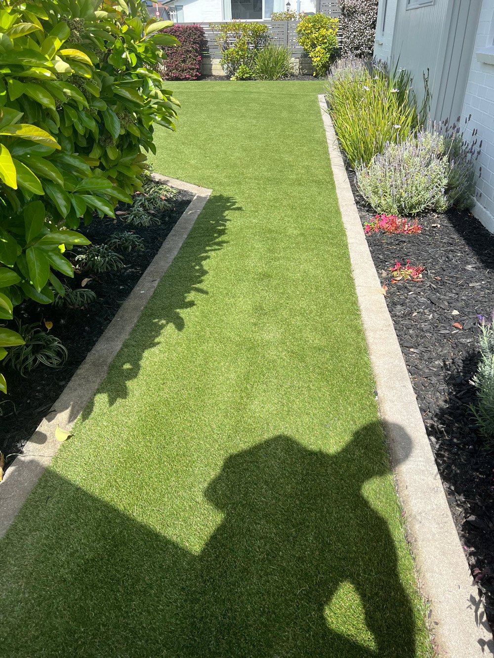 Perfectly trimmed lawn edges on a grass walkway outlined with concrete and gardens on either side