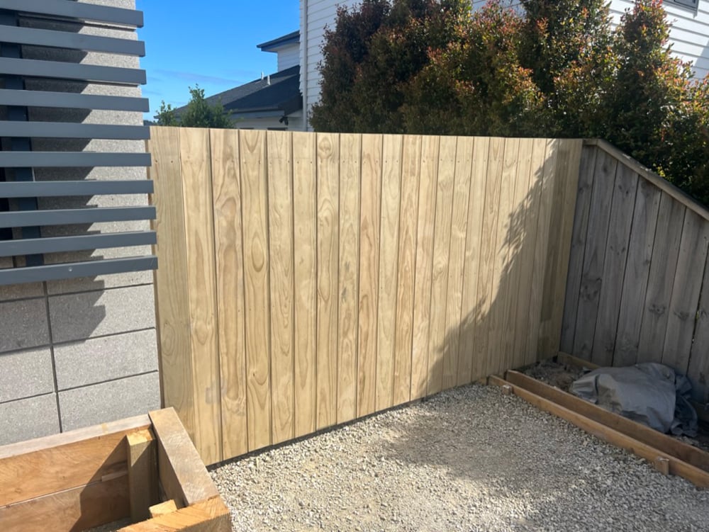 Newly installed unstained fence blocking off the backyard from the street and ensuring privacy for the home