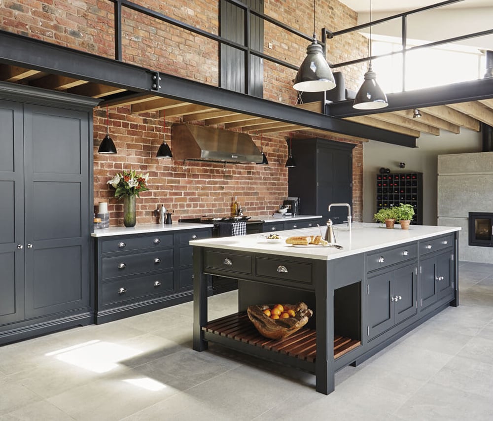Industrial kitchen with a spacious island, brick splashback, and plenty of room for cooking food for any amount of people