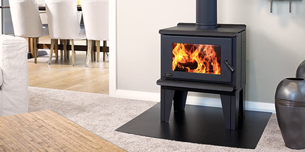 Freestanding black wood fire on a black platform protecting the beige carpet in a modern white furniture with birch wood accents