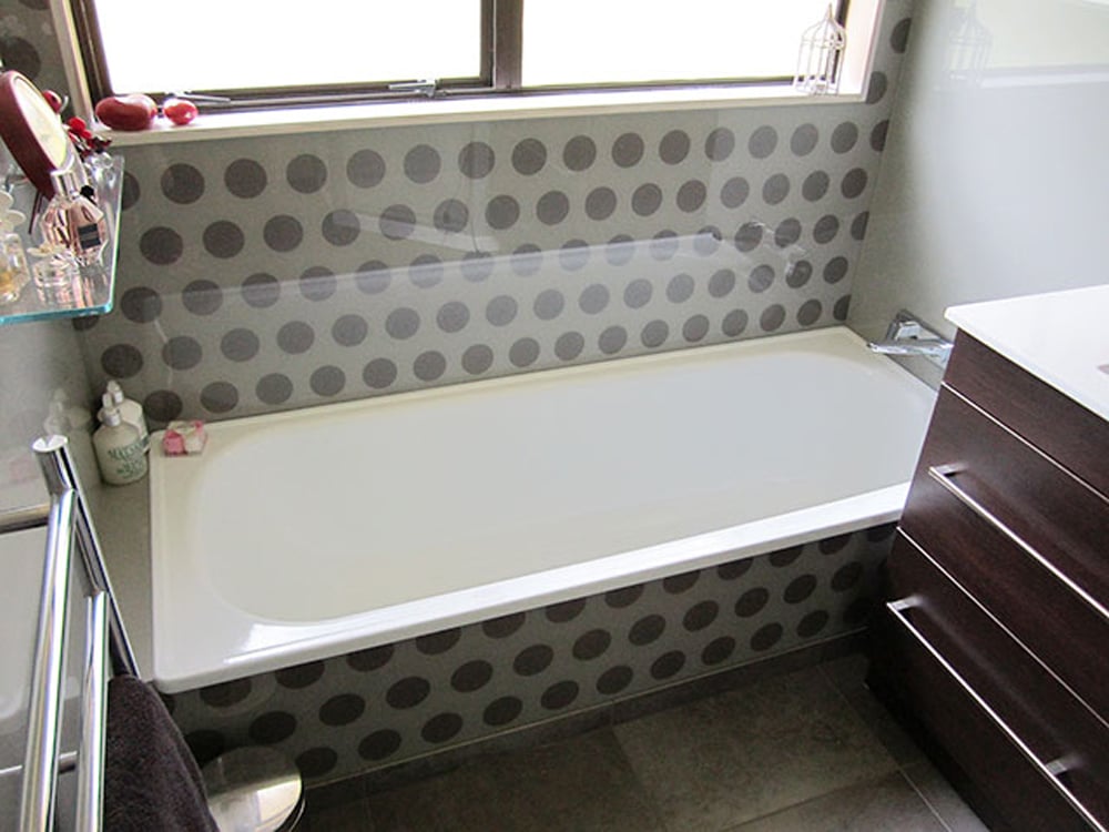 White bath with a polka dot pattern on the splashback that matches the side of the bath