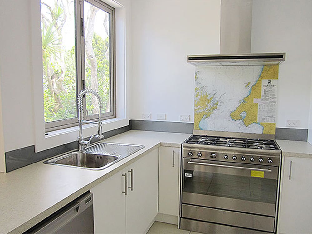 Predominantly white kitchen with a large industrial-looking oven and a splashback above it with a map of part of the world on it
