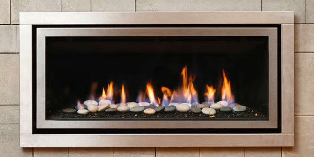 Beige stone tiled wall with an aluminum-framed built-in gas fire that displays stones