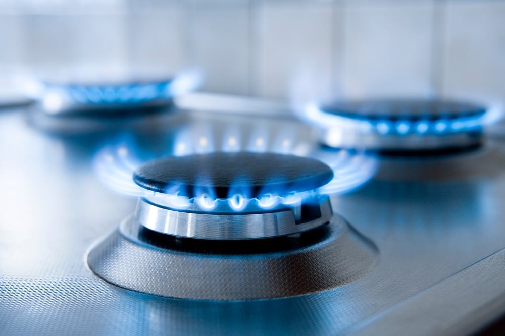 Silver stovetop with three gas hobs burning blue with nothing on them