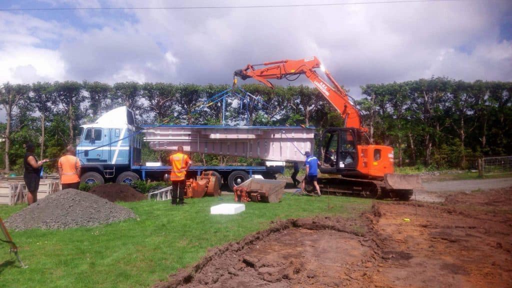 Orange digger lifting a pool off the back of a truck to put in the ground for an Auckland resident
