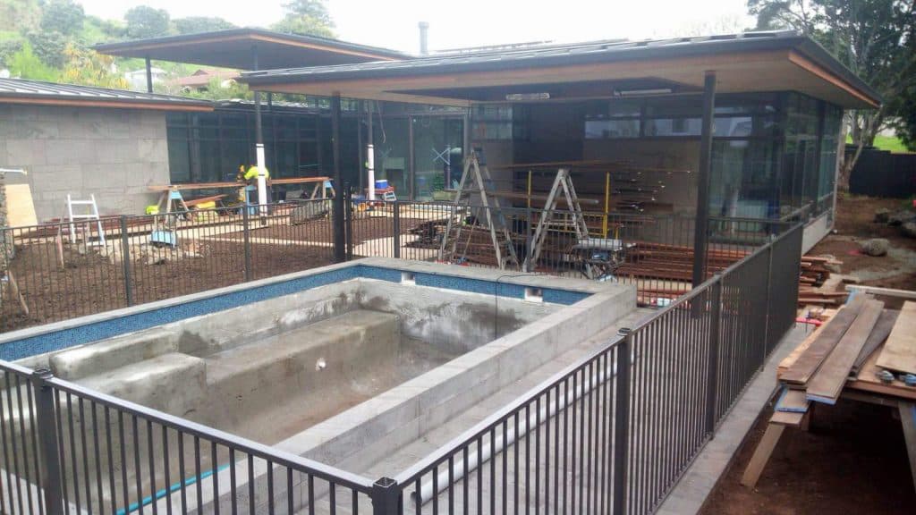 Unfinished backyard with a newly poured concrete pool and an excavated yard ready for new soil and grass