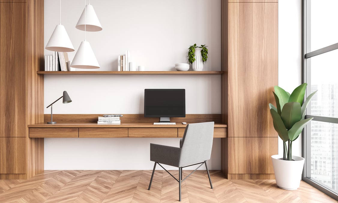 Sleek wooden office space with a white backdrop and tall wood cabinets on either side for storage space