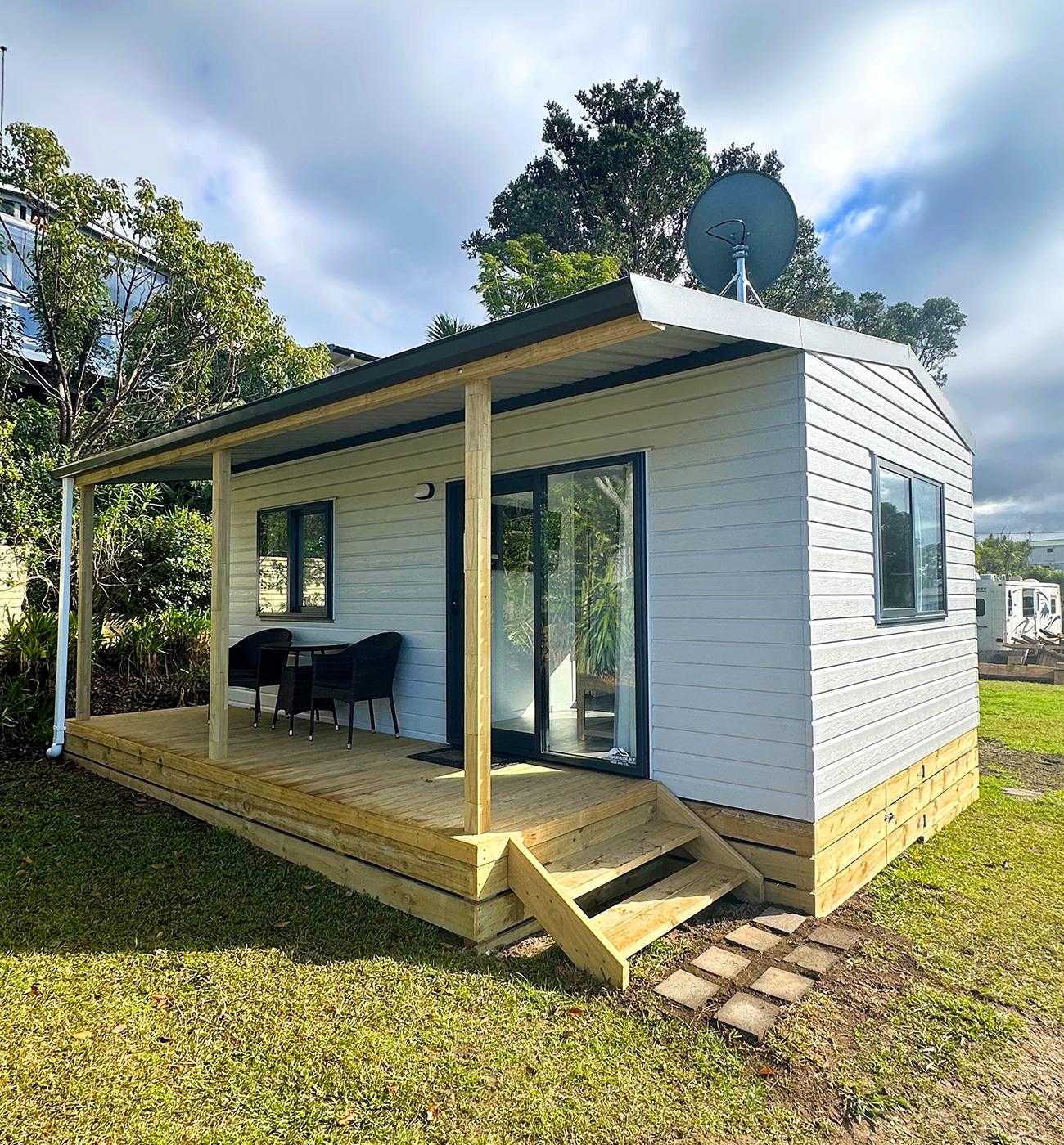 1 bedroom cabin accommodation with a front porch and two steps located at Pinewoods Holiday Park on the Hibiscus Coast