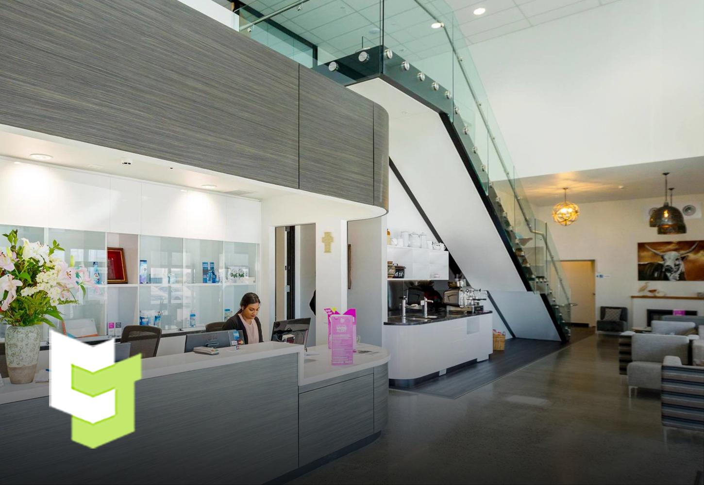 Hotel reception with white walls and ceilings and bright white lights, well-contrasted with Colourform Joinery's grey wood panels