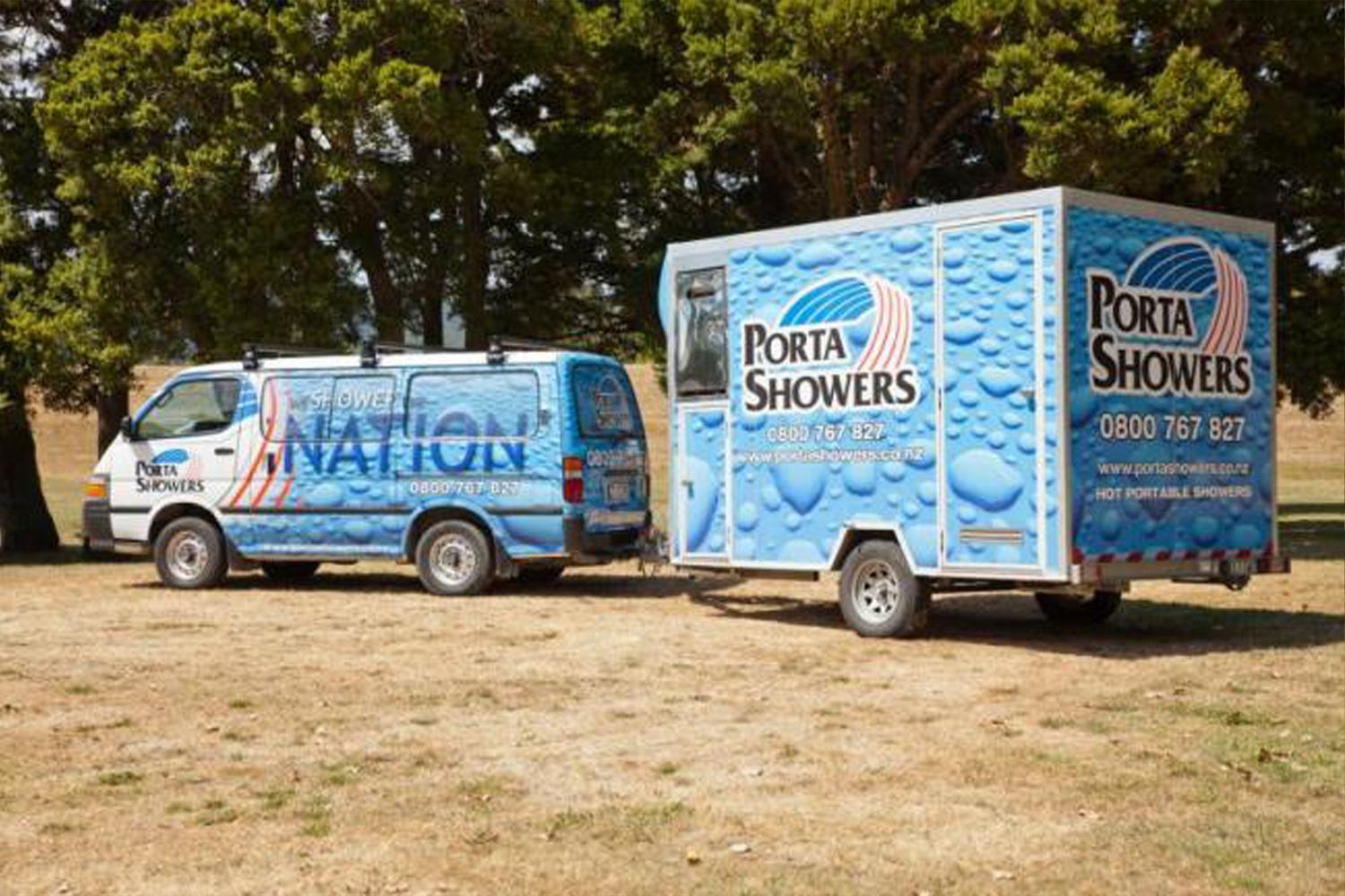 Porta Shower van towing a portable shower trailer unit parked in a dead grass field with trees covering the background