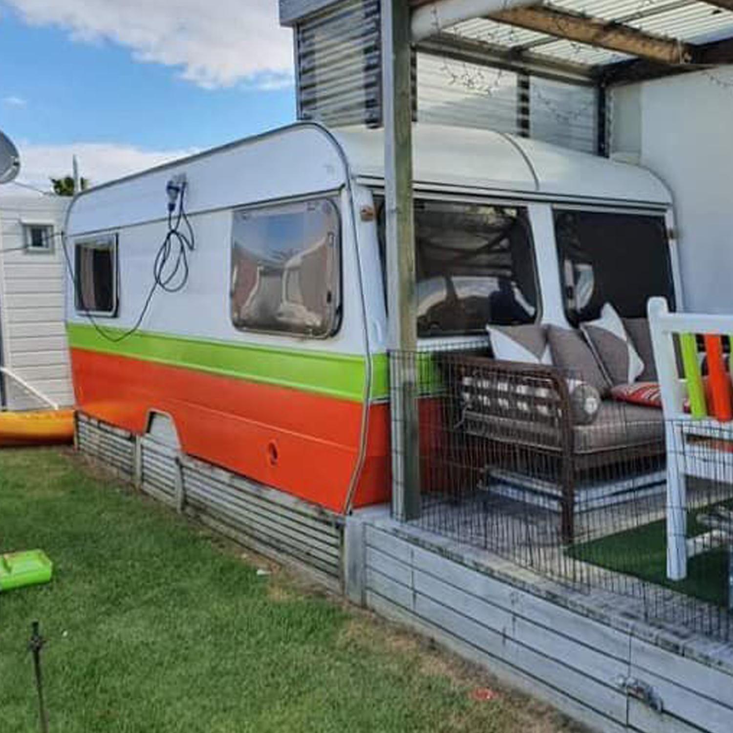 Converted caravan sleepout with orange and green painted bottom-half and a white top