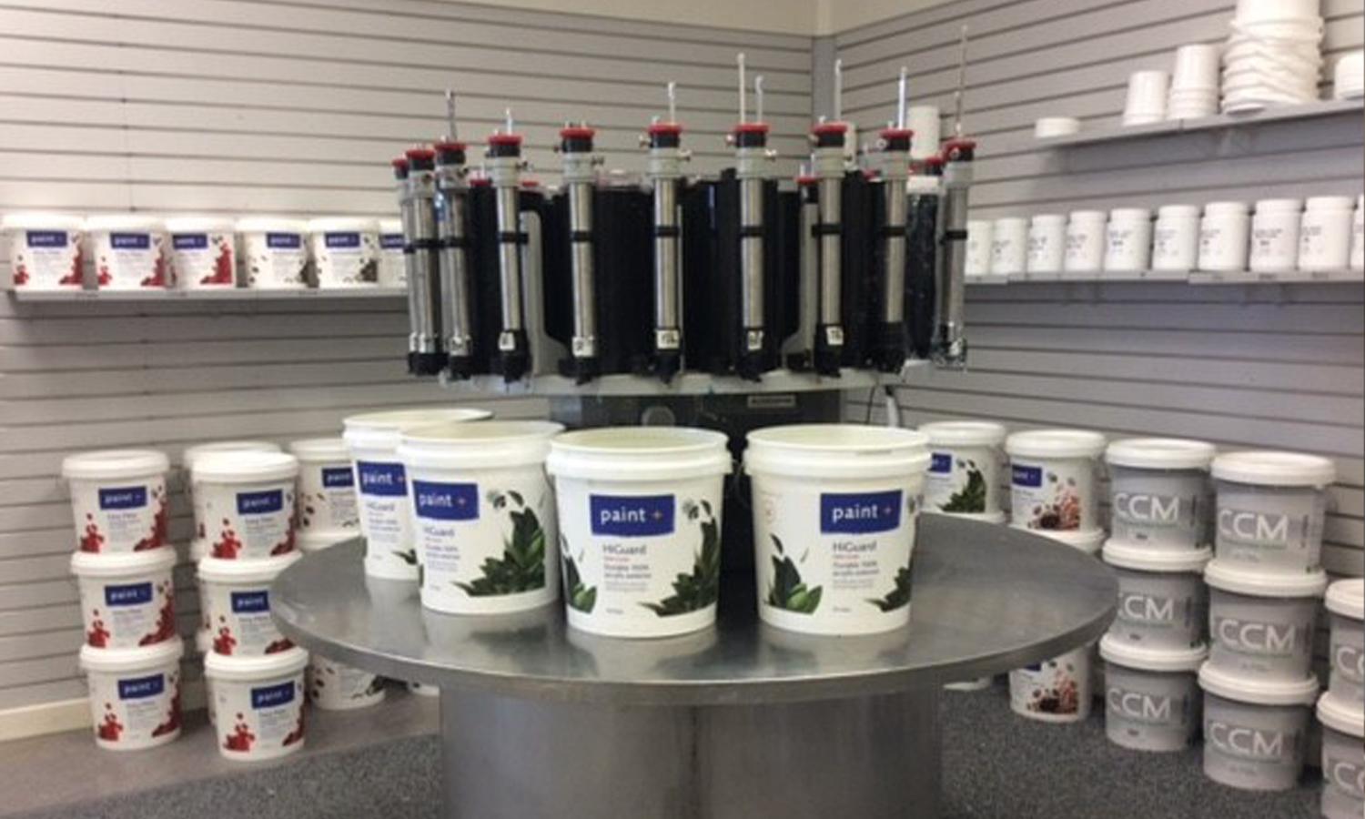 Inside view of the corner of a paint store with all different sizes of paint buckets stacked high