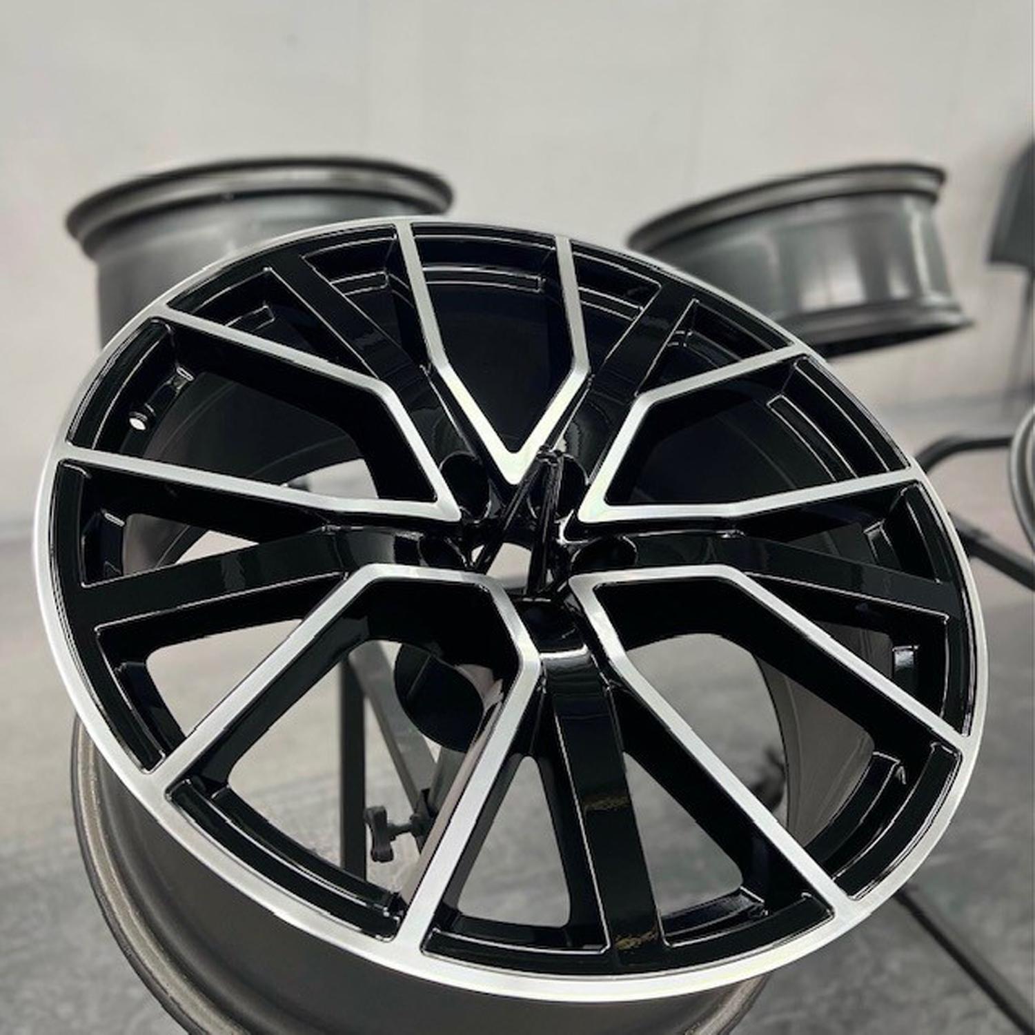 Silver rim with black painted accents sitting on a metal stand amongst other rims