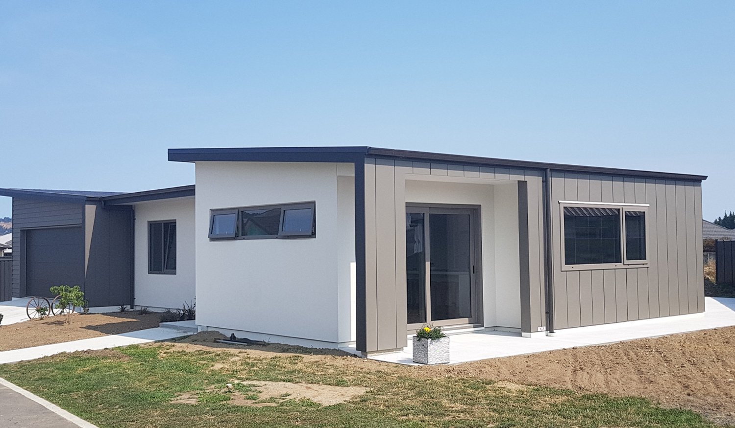 Modern newbuild home with a white, grey and black exterior and dark upvc window and door frames
