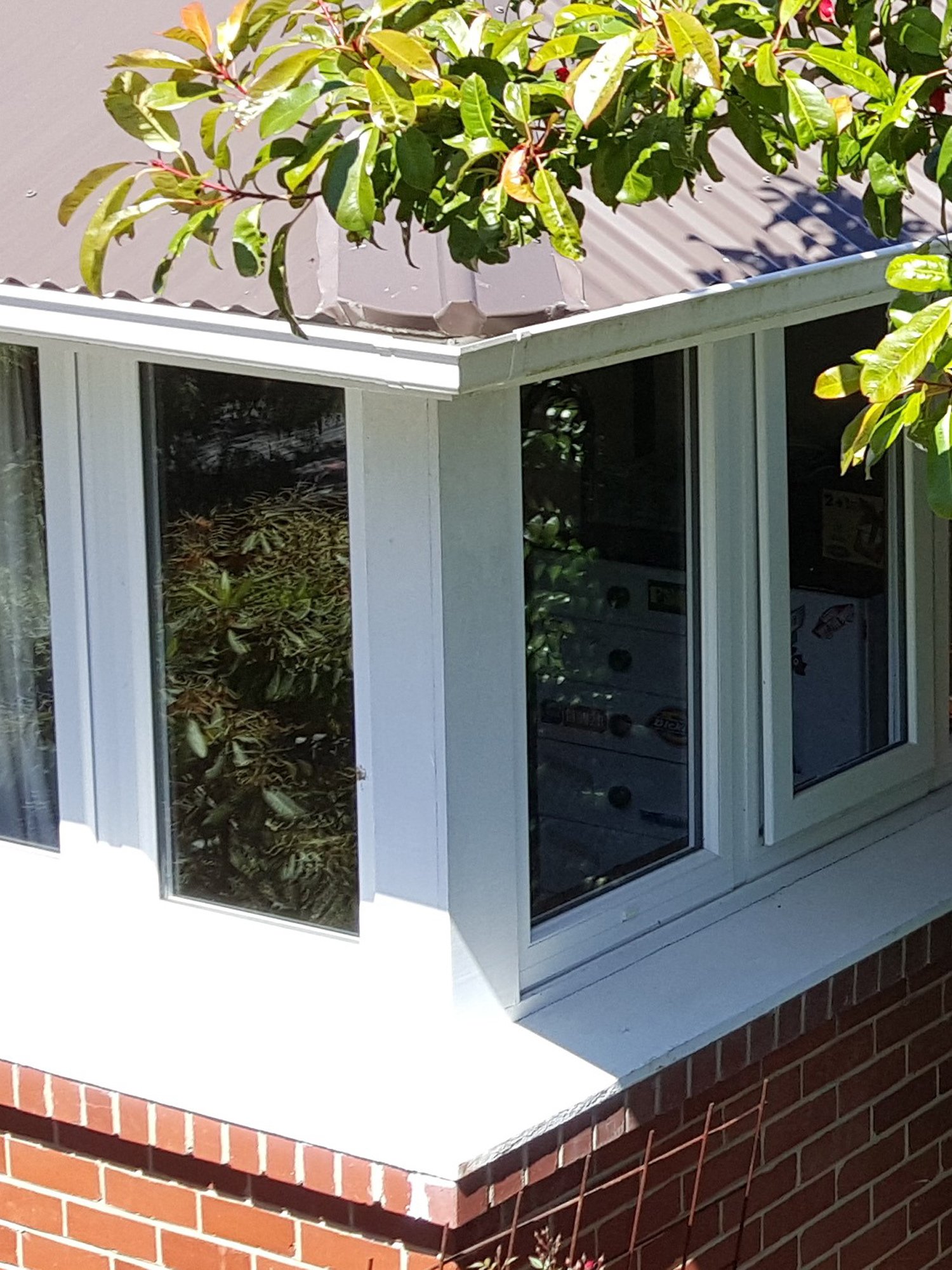 Box bay window with brown coloured upvc window framing on a yellow-white brick house