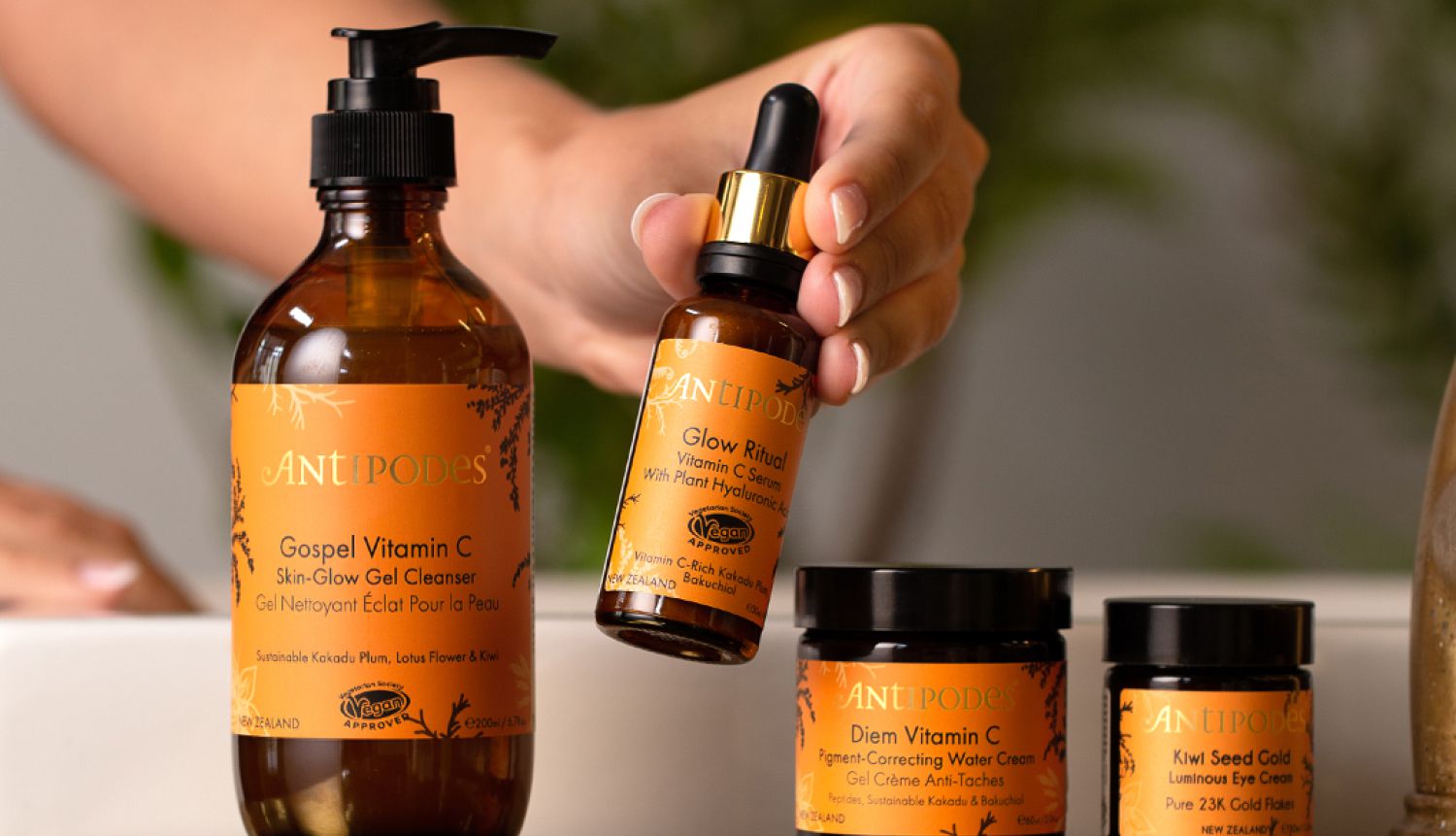 Range of different Antipodes skincare products on display with one of of Pretty Good Facials' members holding one up