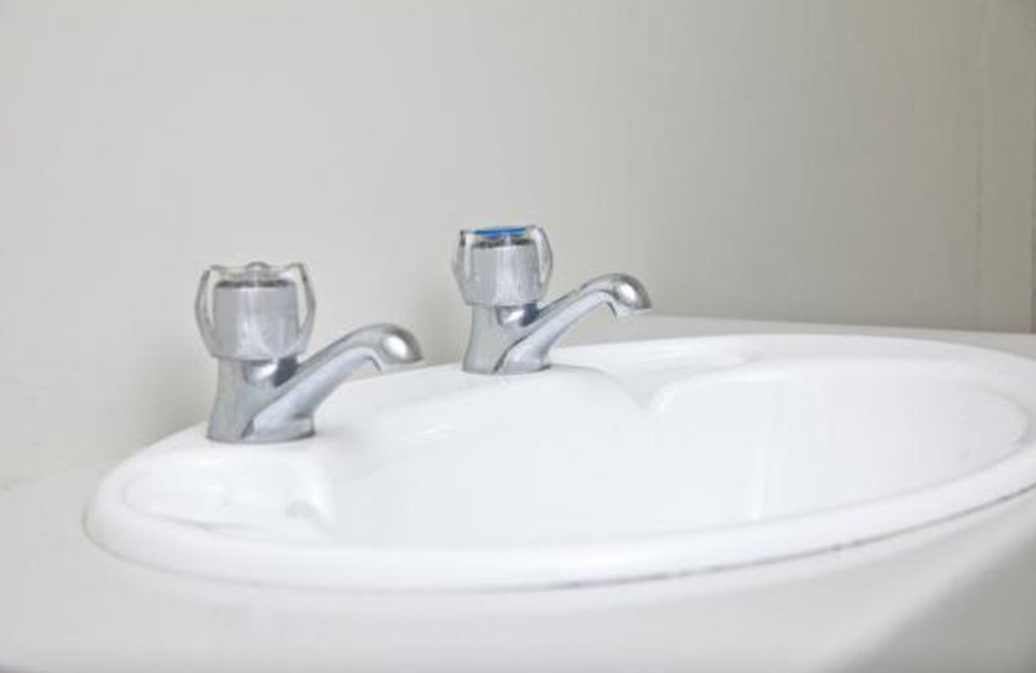 White sink with metal taps and clear tap handles in one of Porta Showers' portable trailer units