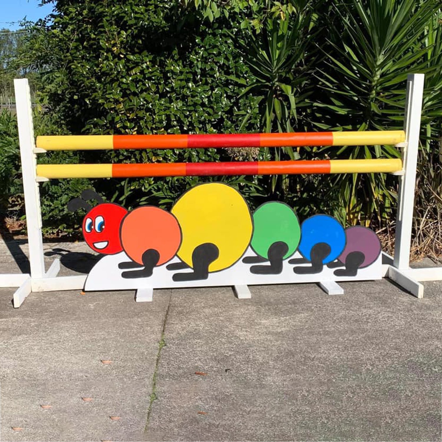 Colourful caterpillar under a horse show jump painted with yellow orange and red paint