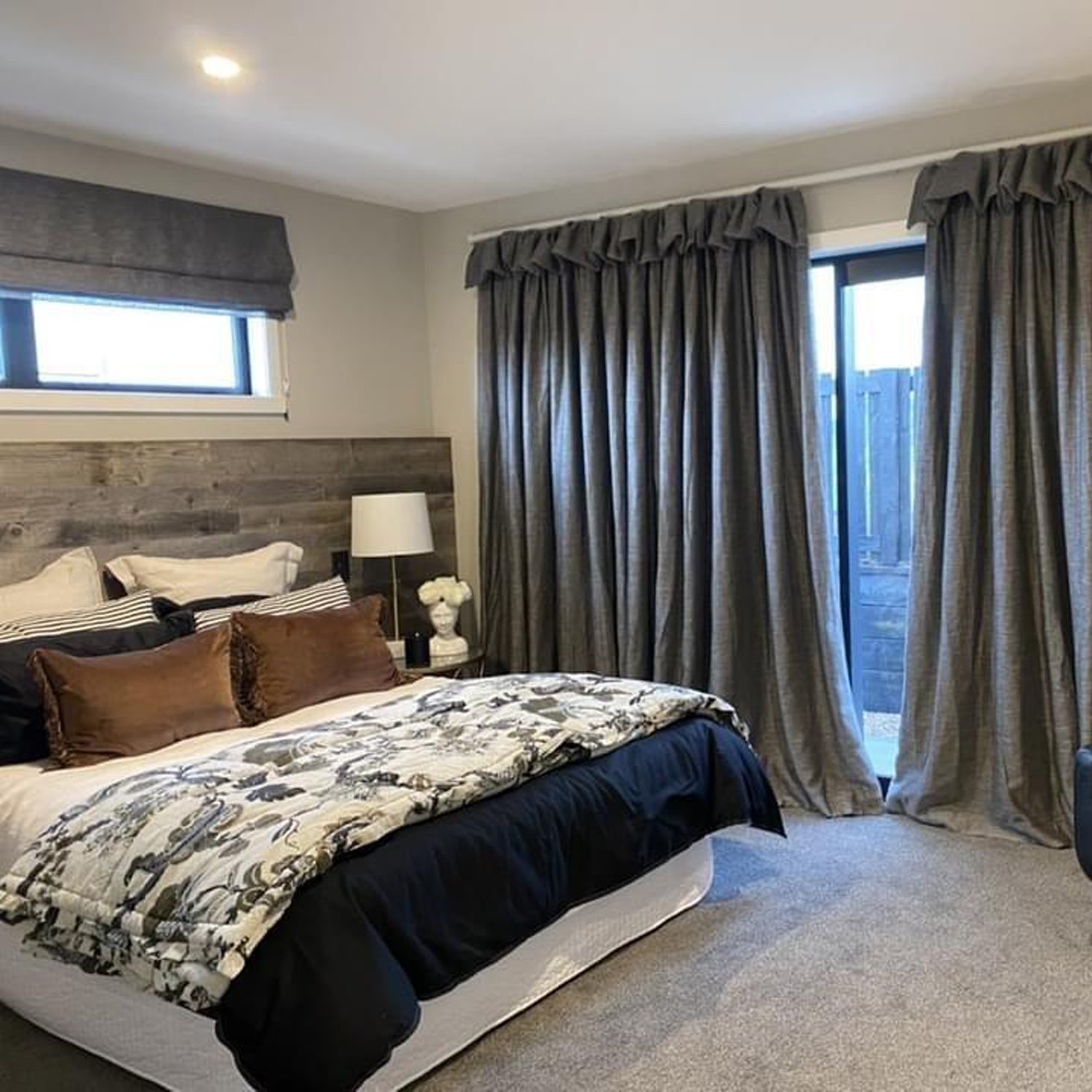 White painted interior walls of a bedroom with complimenting grey curtains and white and black duvet on the queen-sized bed
