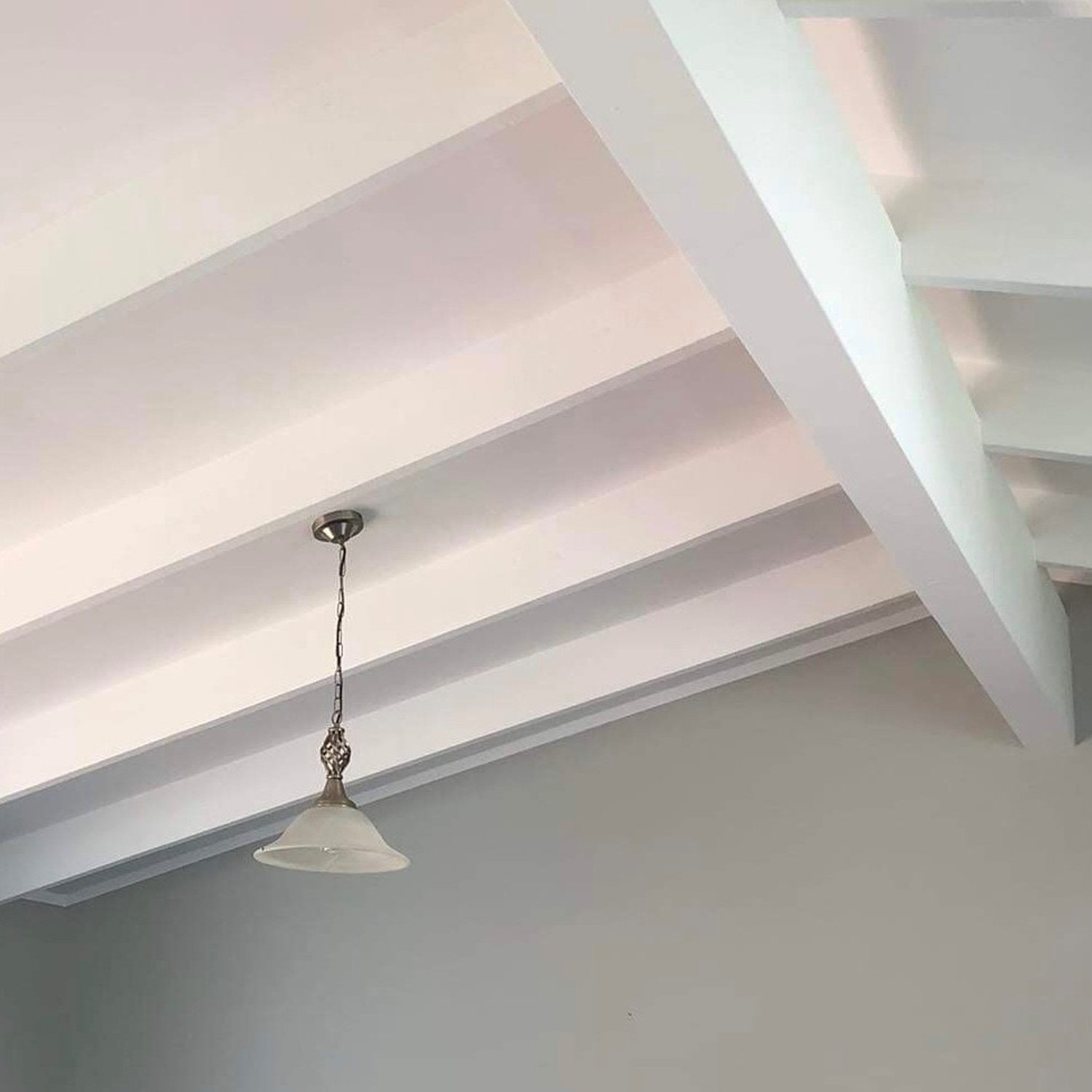 Light grey painted wall and a white painted ceiling with a light hanging