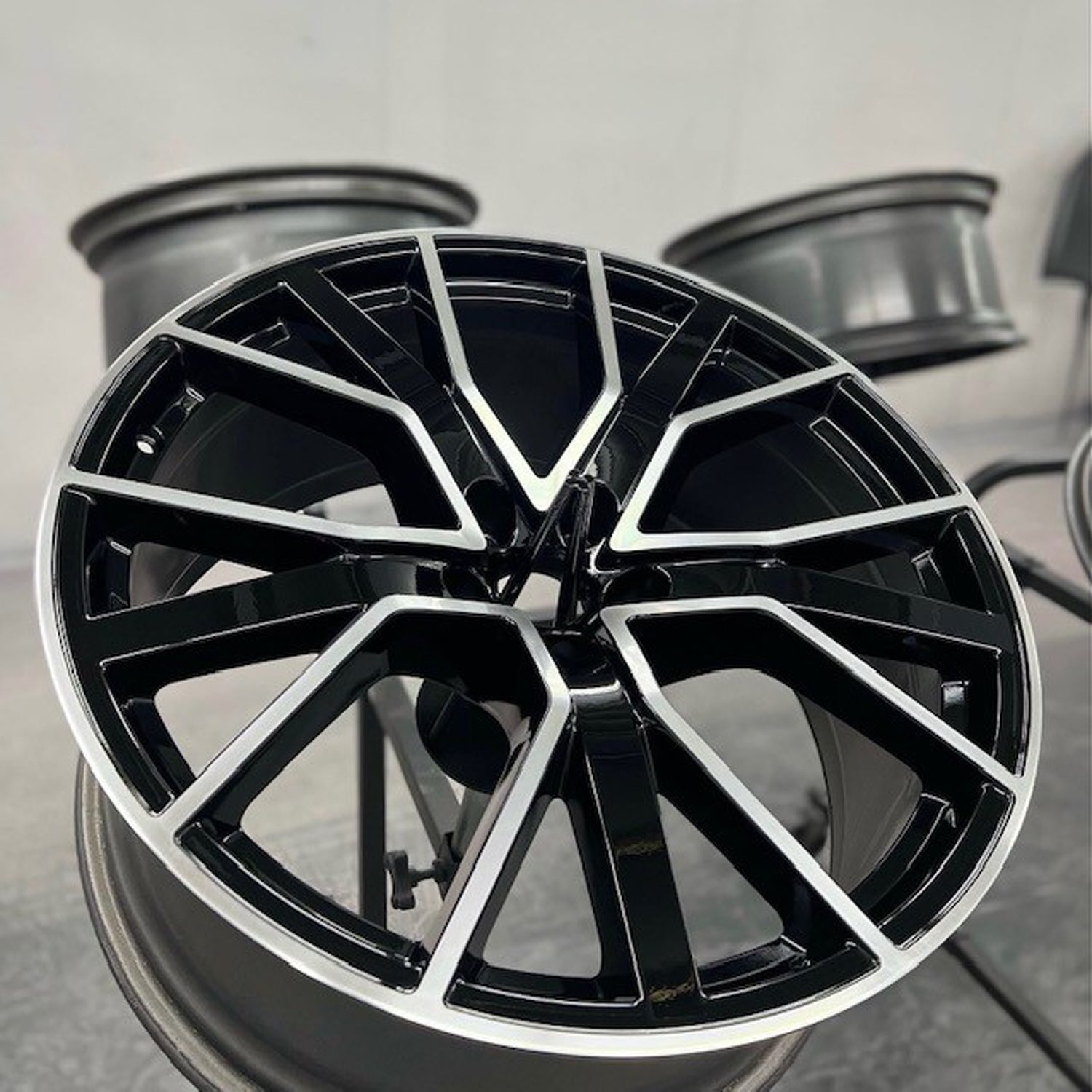 Silver rim with black painted accents sitting on a metal stand amongst other rims