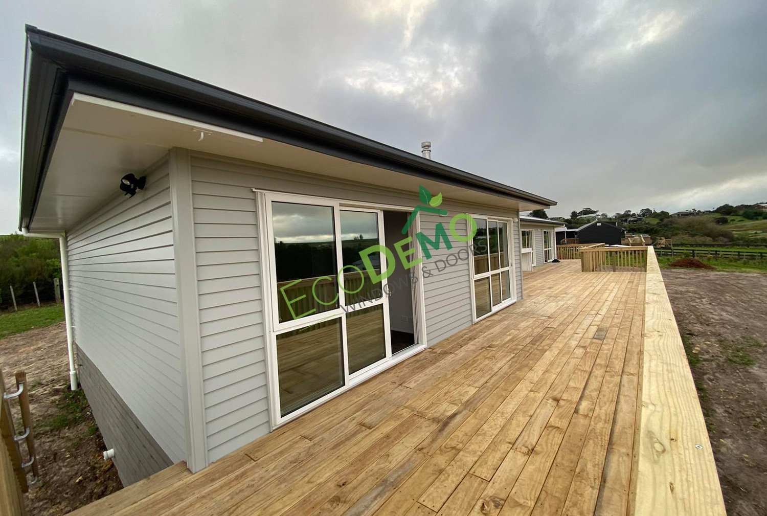 The outside of a new home and deck with white aluminium doors - linking to the aluminium door profiles page