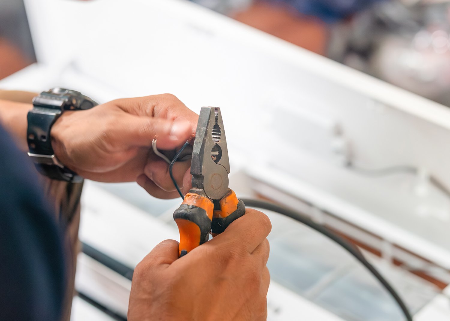 Hand of an Electrician with plyers cutting an electrical wire - Links to Domestic Electrical Page